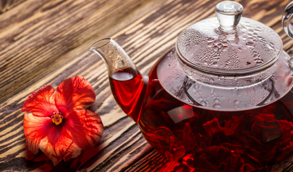 Et bilde av en vannkoker i glass full av rød hibiskuste, som er vanndrivende og kan brukes til å senke blodtrykket naturlig; men bør brukes sammen med en leges råd.
