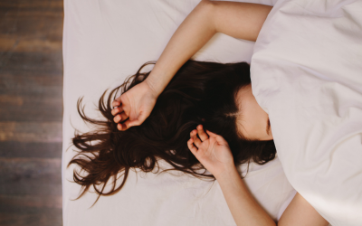 Woman sleeping in bed, face hidden under the blanket