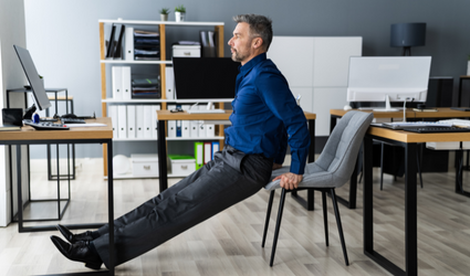 En forretningsmann gjør stoløvelser ved skrivebordet sitt for å ha en sunnere livsstil og forbedre produktiviteten på jobben