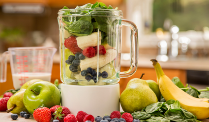 Sunn mat lagt ut på et bord med en blender full av frisk frukt som viser en livsstil med å spise sunt.