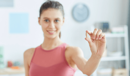 En kvinne som holder frem et vitamin D-kosttilskudd i hendene