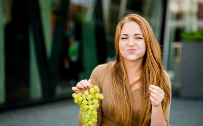 Smiling woman eating grapes