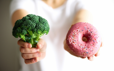 Person holding broccoli and a doughnut 