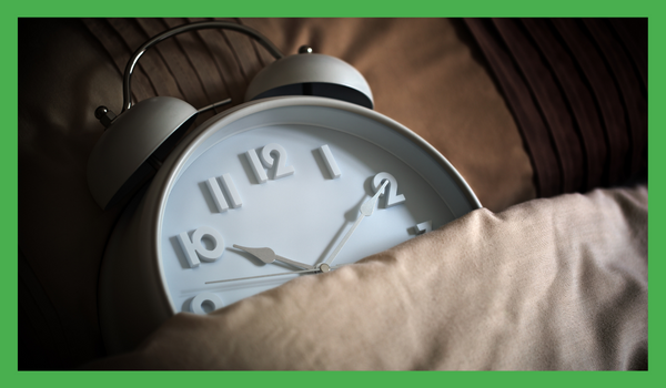 En vekkerklokke som er gjemt i sengen, og illustrerer viktigheten av regelmessig å få nok søvn