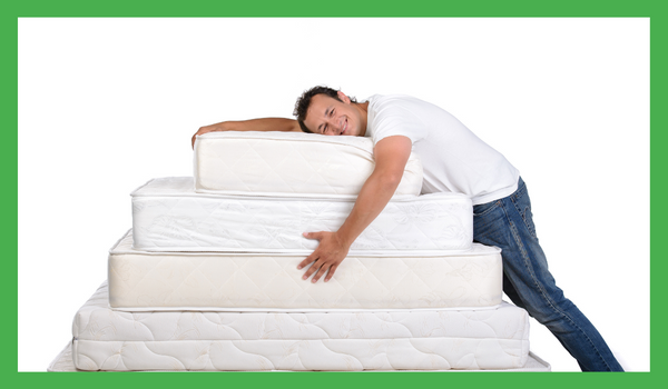 En glad mann ligger og gir en klem til en haug med madrasser i ulike størrelser i midten av en hvit bakgrunn. 