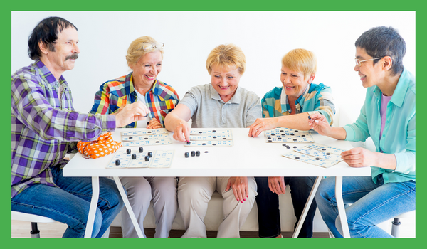 Flere glade eldre venner samlet rundt et bord og spilte et spill som demonstrerte fordelene med sosiale relasjoner på ens helse